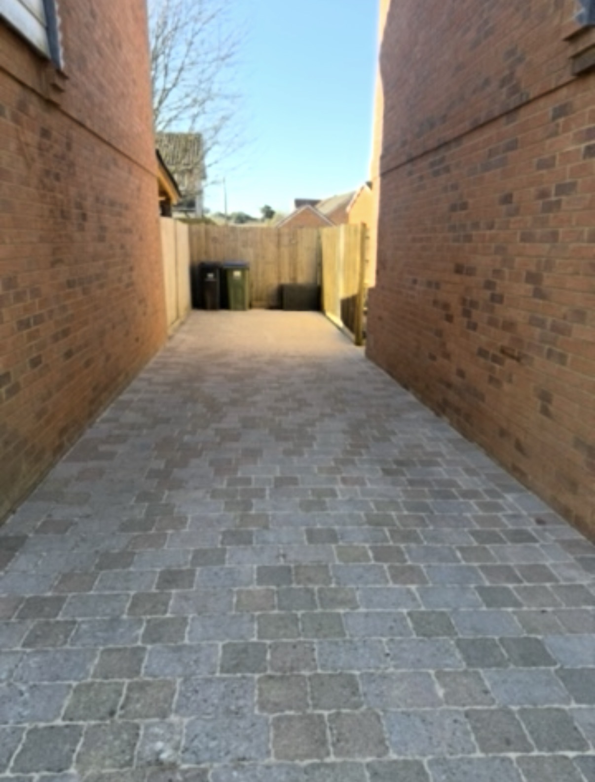 Block-paved driveway freshly jet washed between brick walls